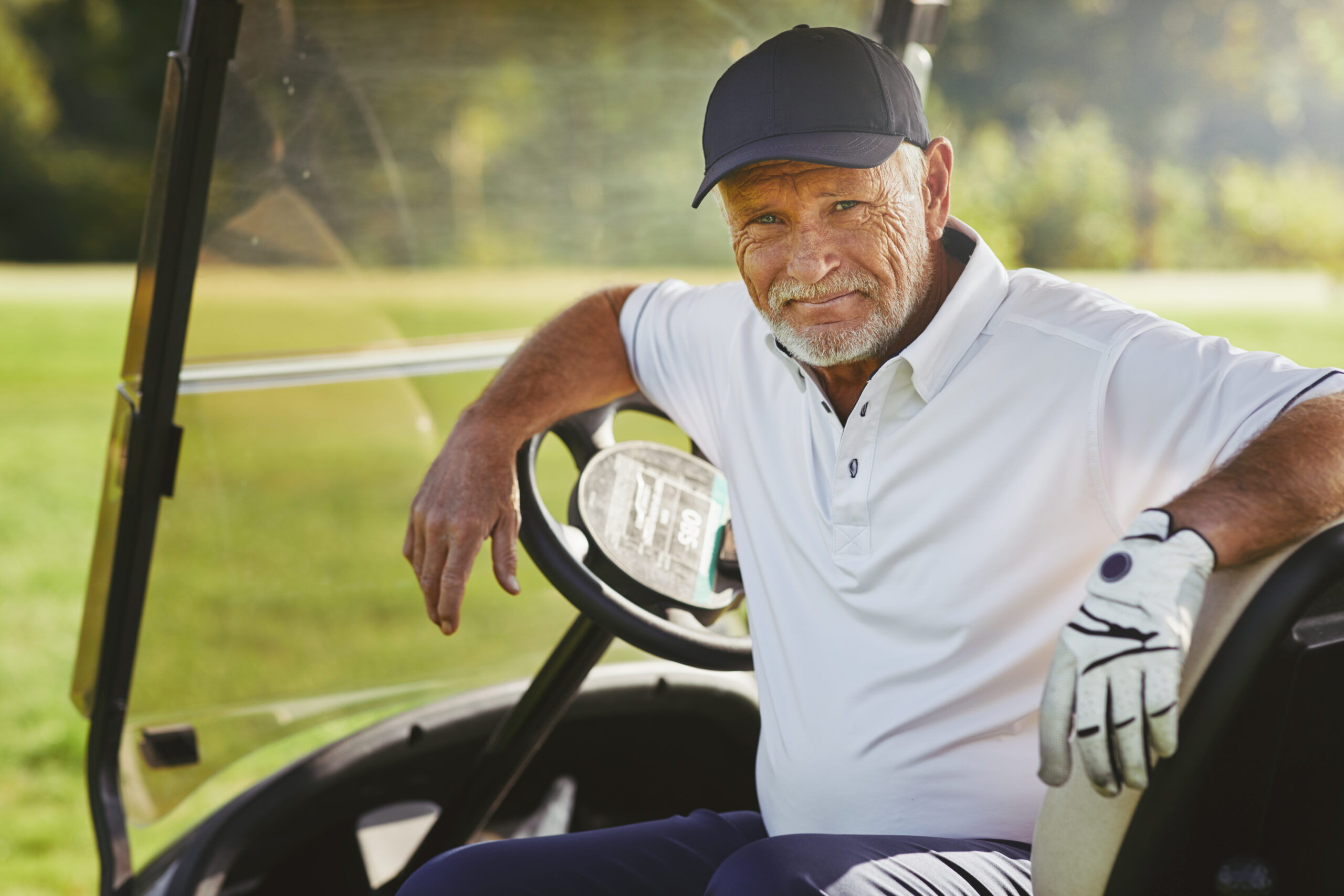 Senior Man Smiling While Sitting In A Cart Enjoying his golf